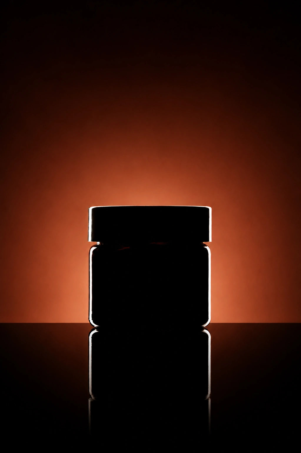 Dark glass jar with a reflective surface on a black background