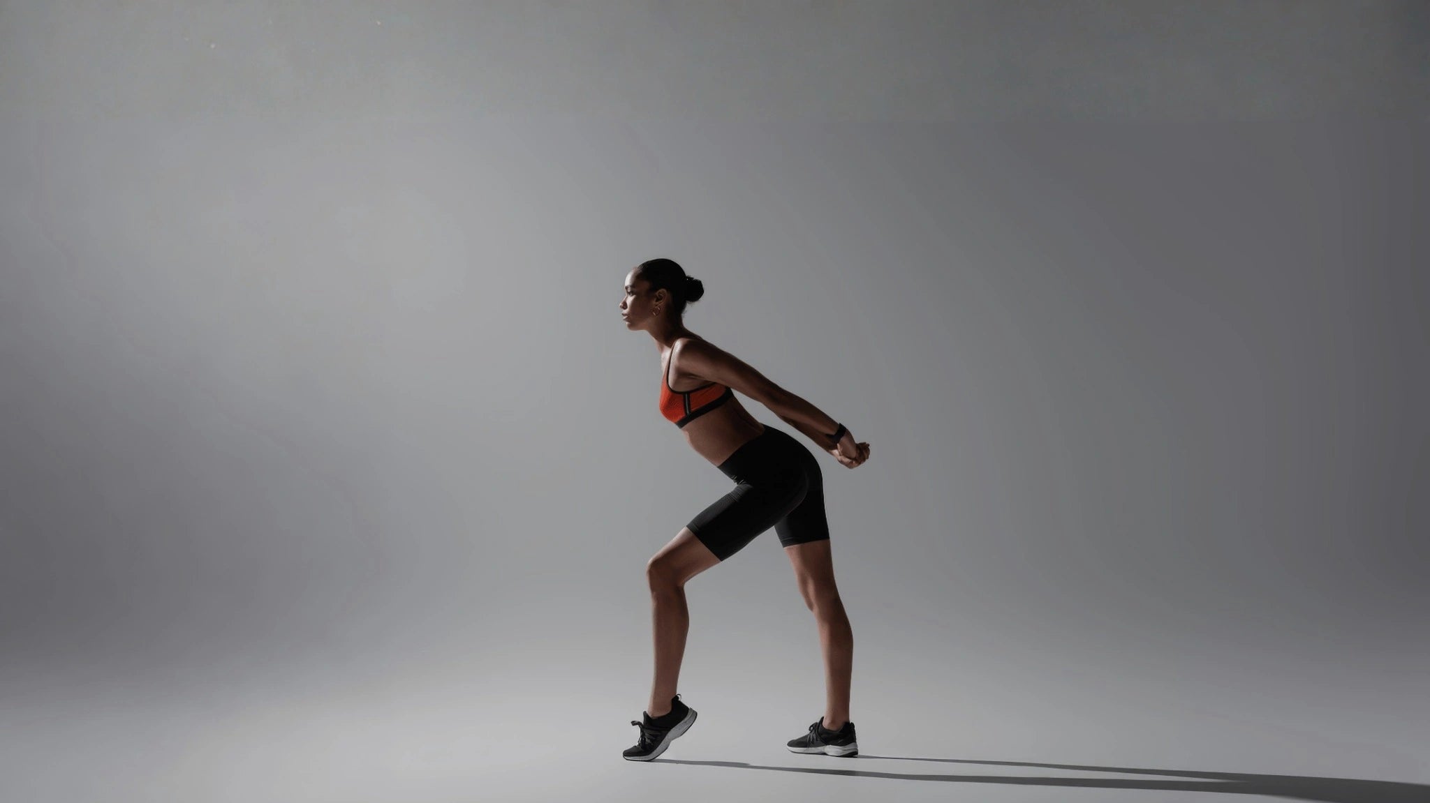 woman in athletic wear standing against a gray background